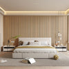 A modern bedroom featuring a light wood slat wall, white bedding, and neutral tones.