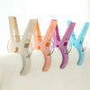 A row of colorful heavy-duty laundry clips for sheets and towels in various pastel shades.