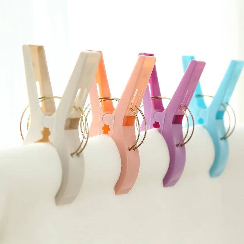 A row of colorful heavy-duty laundry clips for sheets and towels in various pastel shades.