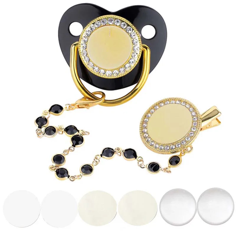 A sparkling rhinestone pacifier with a gold clip and black silicone ring for babies.