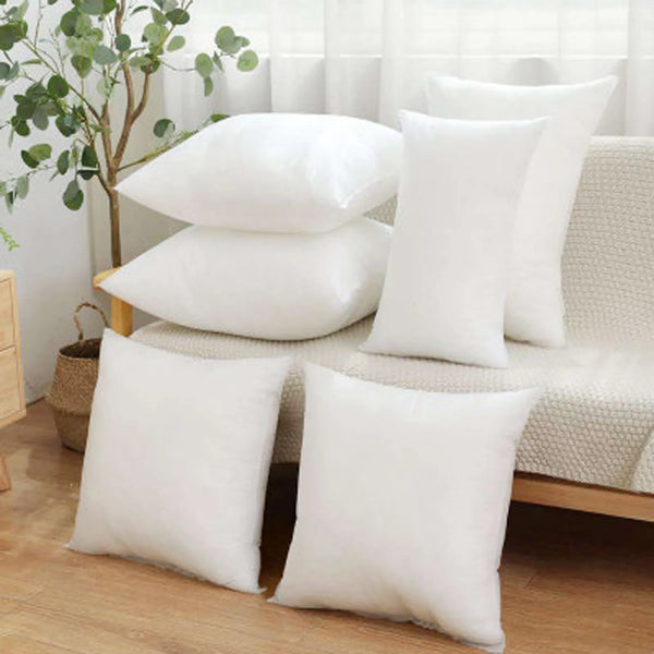A stack of white soft comfort cushions with breathable polyester fill resting on a light-colored sofa.