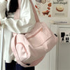 A pink canvas travel tote bag with a strap is being held by a person in a white shirt.