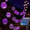 String lights featuring purple Moroccan-style glowing orbs and a solar panel setup at night