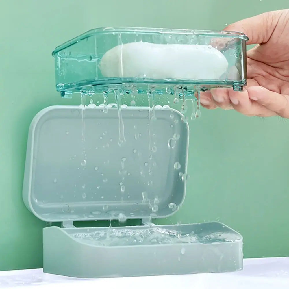 A hand is pouring white soap into a transparent dish, which drains into a larger, rectangular soap holder.