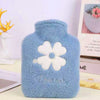 A light blue plush-covered hot water bottle with a white flower design and the word Dreams embroidered on it.