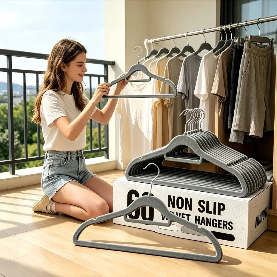 A woman is hanging clothes on velvet non-slip hangers with 360° rotating hooks in a bright indoor setting.