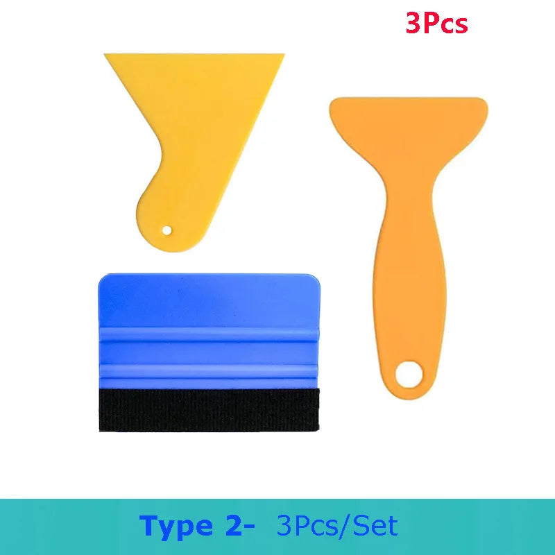A set of three vinyl wrap and film application tools including a yellow spatula, an orange spatula, and a blue tool.