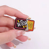 A hand holds a vintage airline ticket enamel brooch set featuring gold foil details on a black and pink background.