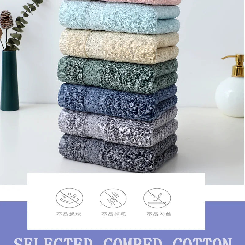A stack of six textured cotton face towels in various shades of blue and green on a white surface.