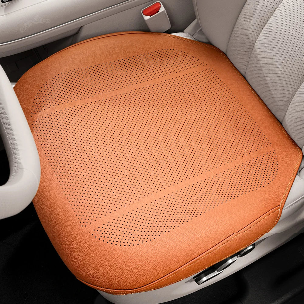 An orange breathable leather car seat cushion is shown placed in a white car seat interior.