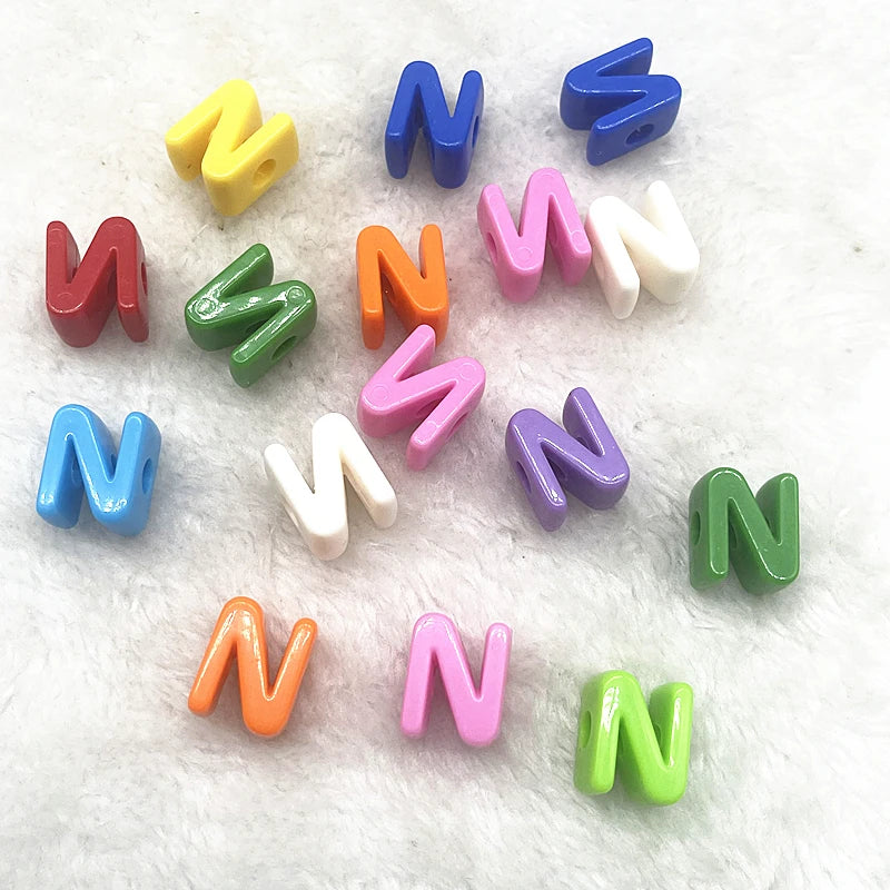 A collection of ten mixed alphabet letter beads in various colors including blue, yellow, green, and pink, scattered on white