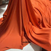 Flowing orange-brown stretch jersey fabric draped in soft folds for decor
