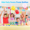 A table display of colorful party favors including balloons, pom-poms, and small toys for a kids party.