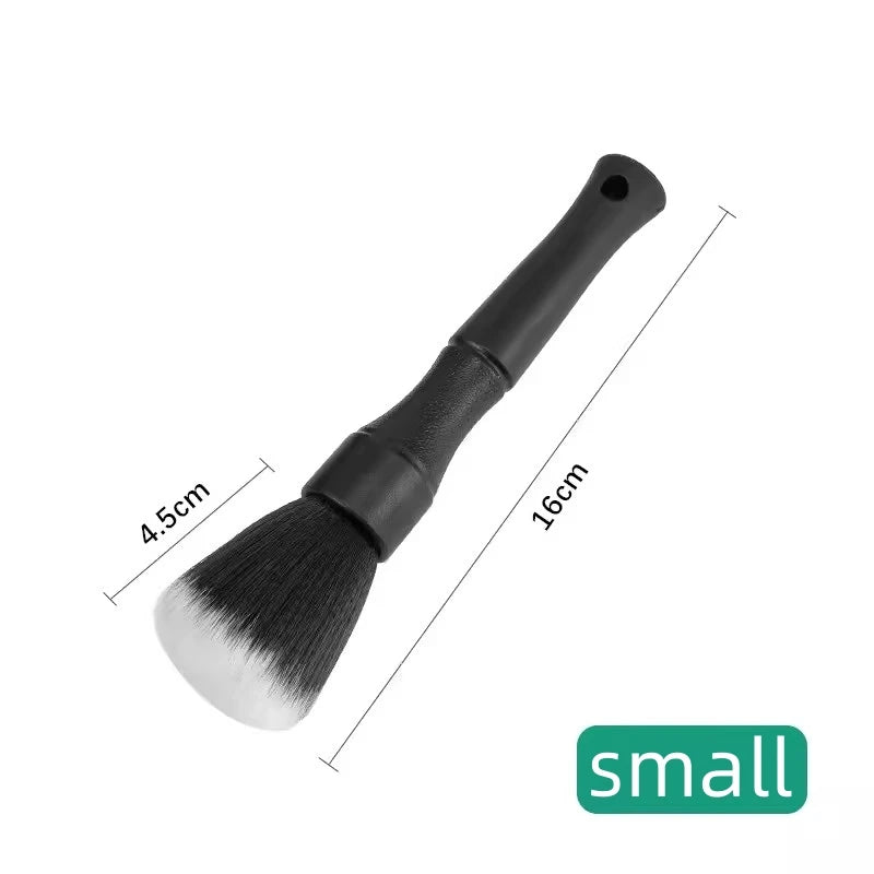 A black soft bristle detailing brush with a handle and wide bristles is shown against a white background.