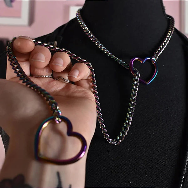 Primer plano de un collar de cadena cubana de acero inoxidable con colgantes de corazón, exhibido sobre terciopelo negro.