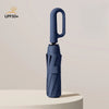 A dark blue fully automatic windproof folding umbrella standing upright on a light surface.