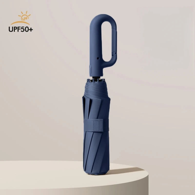 A dark blue fully automatic windproof folding umbrella standing upright on a light surface.