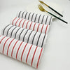 A stack of striped lint-free kitchen dishcloths in white and red are displayed next to a gold fork and knife.