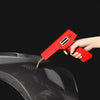 A hand holds a red plastic welding repair kit with staples, applying it to a dark car bumper.