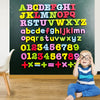 A young child sits in front of a chalkboard covered with colorful magnetic alphabet letters and mathematical equations.