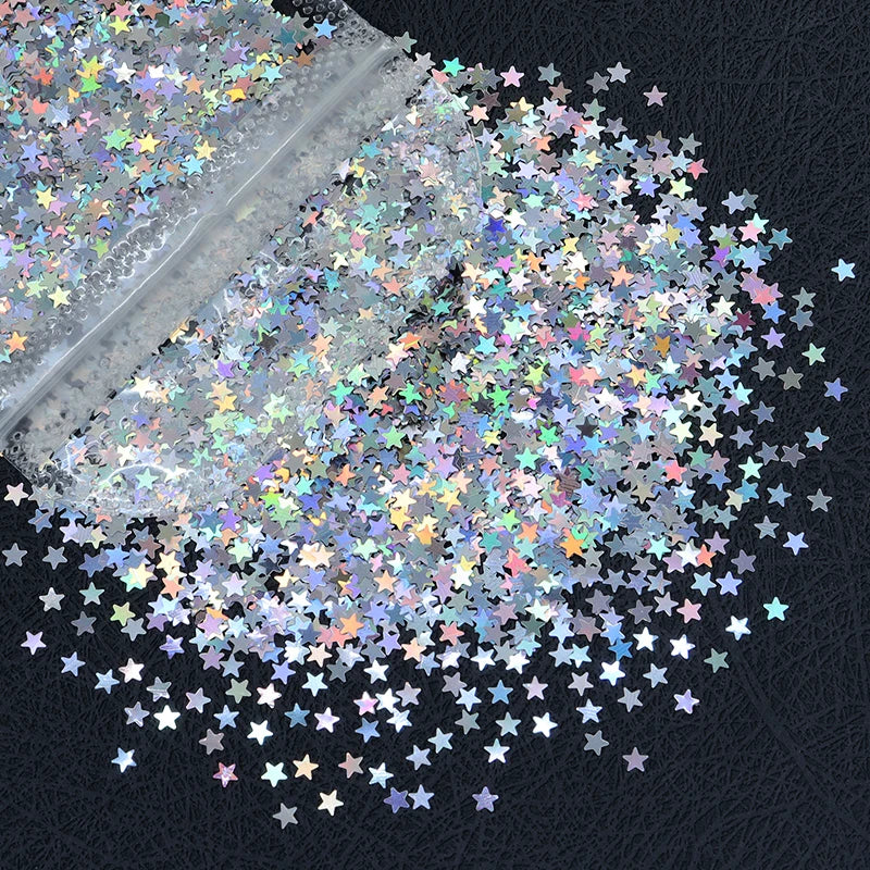 A close-up view of shiny holographic star sequins scattered across a dark surface.