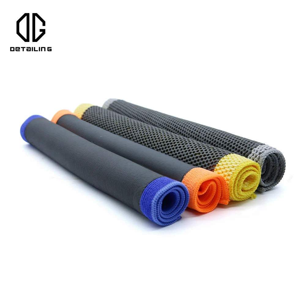 A set of black microfiber detailing towels with colored ends (blue, orange, yellow) rolled up for car paint decontamination.
