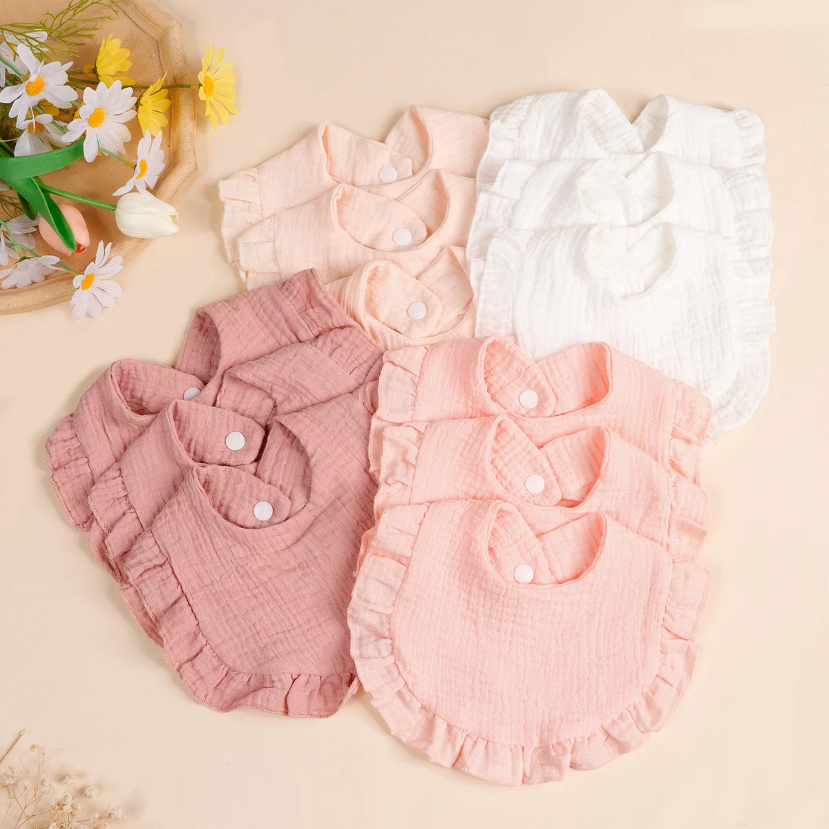 A set of three soft cotton ruffle bibs in pink and white for babies