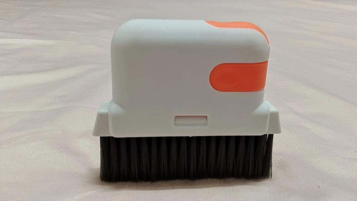 A white and orange multi-purpose crevice cleaning brush with black bristles.