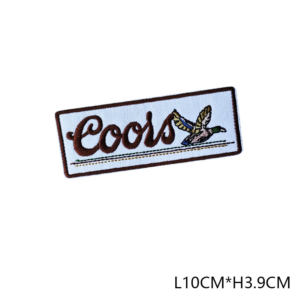 A black and white embroidered patch with the word Coors and a small bird design on a rectangular background.