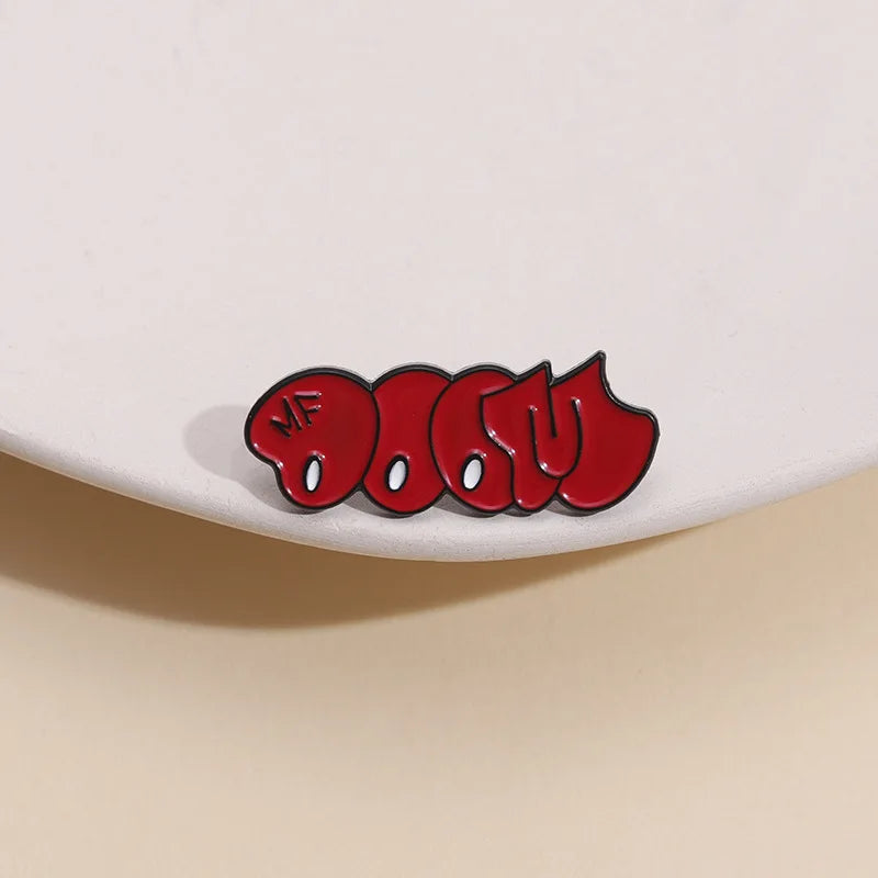 A red enamel pin featuring the text MF DOOM in a bubble font.