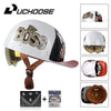 A white motorcycle helmet with a Boss logo and a clear visor, shown alongside accessories like a cap and leather goods.