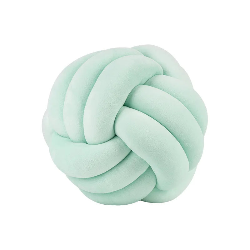 A soft, light mint green knitted or knotted velvet throw pillow with a round shape.