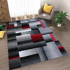 Abstract geometric anti-slip area rug featuring a pattern of black, gray, and red squares on a wooden floor.