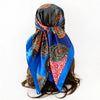 A vibrant blue and black leopard paisley square scarf tied around dark hair.