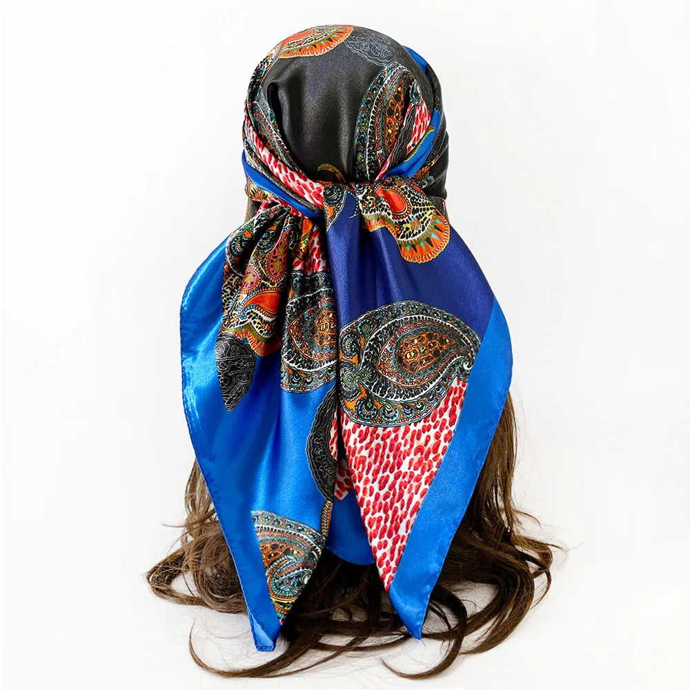 A vibrant blue and black leopard paisley square scarf tied around dark hair.