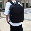 A black compact cabin travel backpack worn by a person standing outdoors.