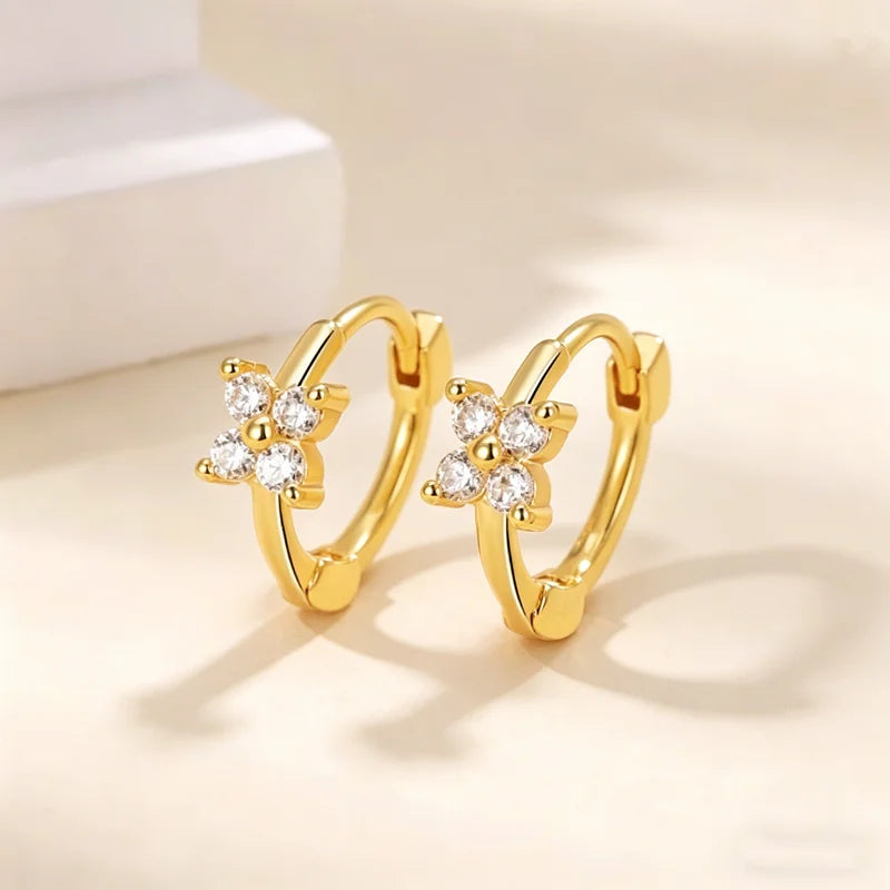 Par de aretes de aro dorados con diseño floral y piedras de circonita cúbica transparente.