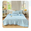 A light blue waffle-weave quilt is displayed on a bed, featuring a soft texture and light blue color.