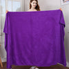 A woman holds up a vibrant purple microfiber bath towel displaying its soft texture and drape.