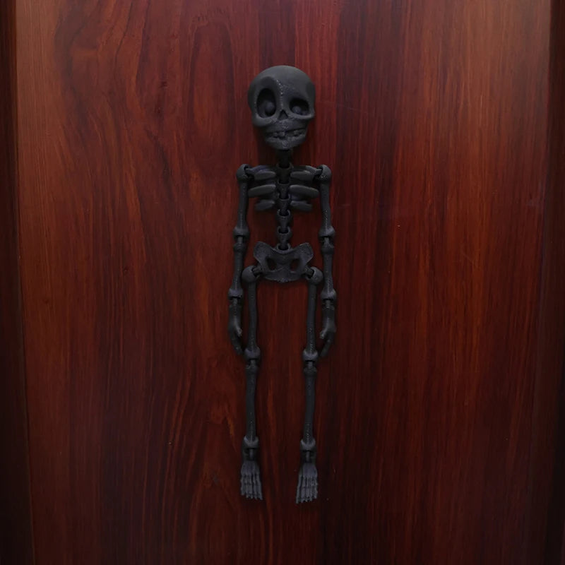 A dark, realistic sculpture of a human skeleton mounted on a wooden surface.