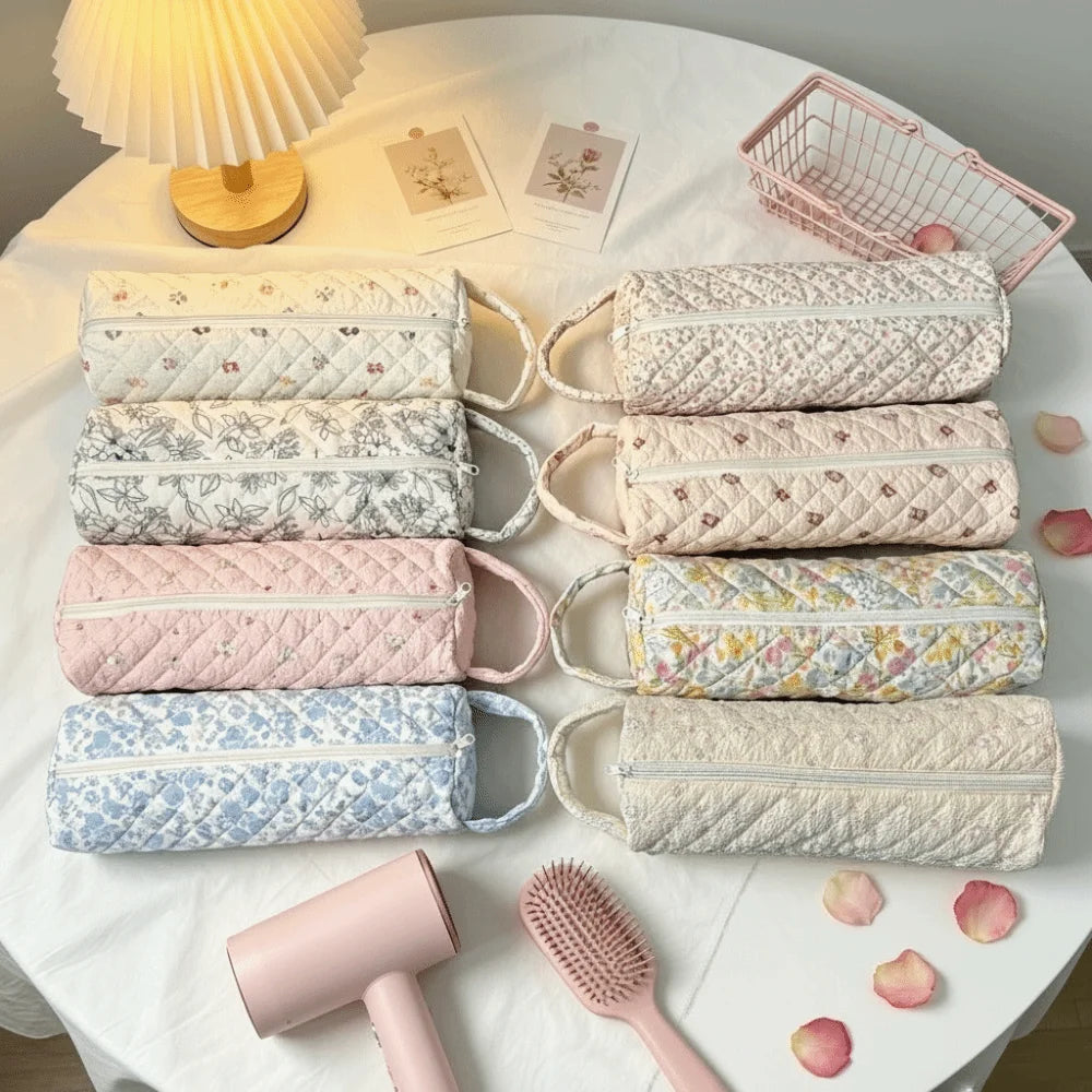A collection of quilted cotton hair dryer storage bags in various pastel colors and patterns displayed on a white cloth.