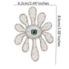 A sparkling beaded rhinestone eye patch with a green iris surrounded by white petals.