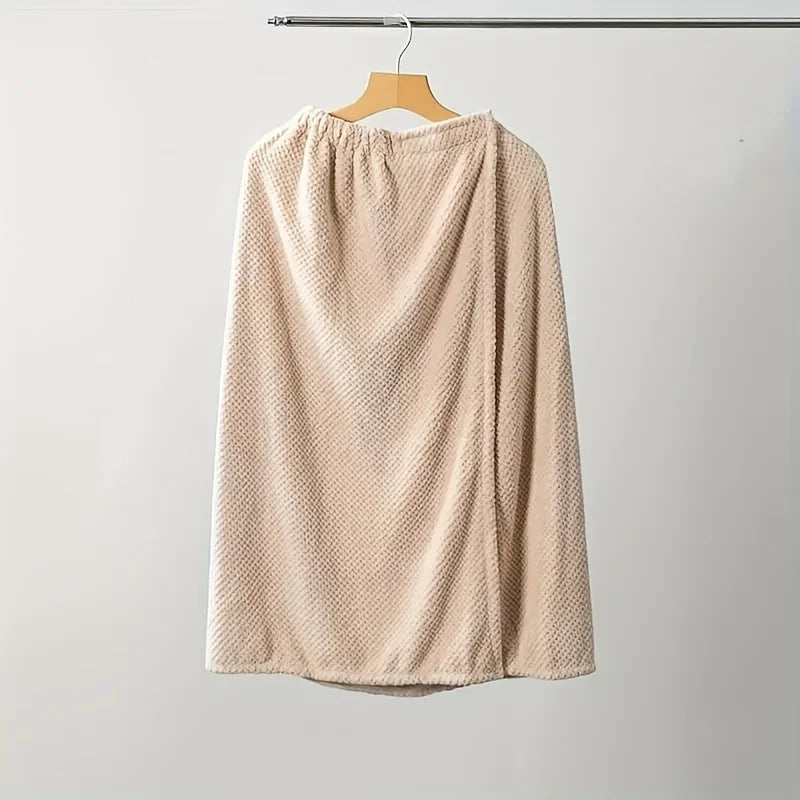A beige, textured women's quick-dry wearable bathrobe towel hanging on a wooden hanger.