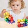 A young child is holding and arranging colorful 3D rotating fidget balls on a wooden surface.
