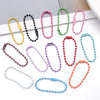 A collection of colorful ball bead chains in various colors like yellow, black, pink, green, and red are displayed on a white