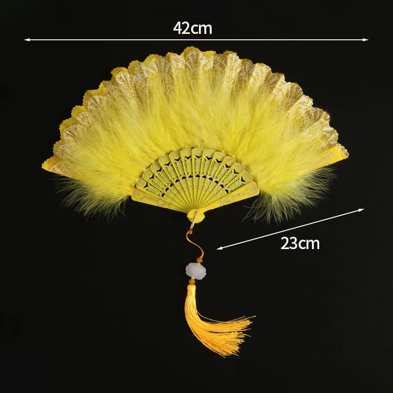 A yellow lace folding hand fan with a decorative fan and a long golden handle.