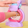 A hand is using a purple and pink DIY friendship bracelet making kit to create a bracelet on an arm.