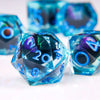A close-up of a translucent blue liquid core resin die with a dragon eye design, resting on a white surface.