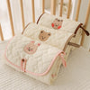 A cream quilted foldable portable diaper changing pad with cute animal embroidery resting on a light surface.
