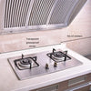 A kitchen stovetop with a transparent greaseproof sticker placed on the surface, beneath a stainless steel exhaust vent.